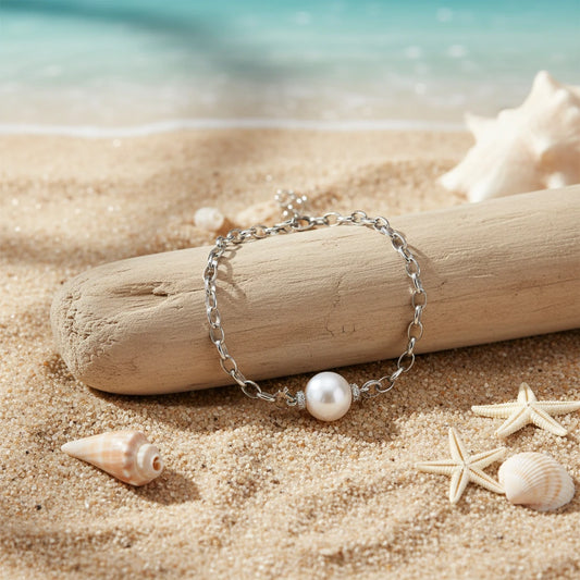 Perlenketten-Armband von flyliving, auf einem Treibholz am Sandstrand mit Muscheln und Seesternen dekoriert.