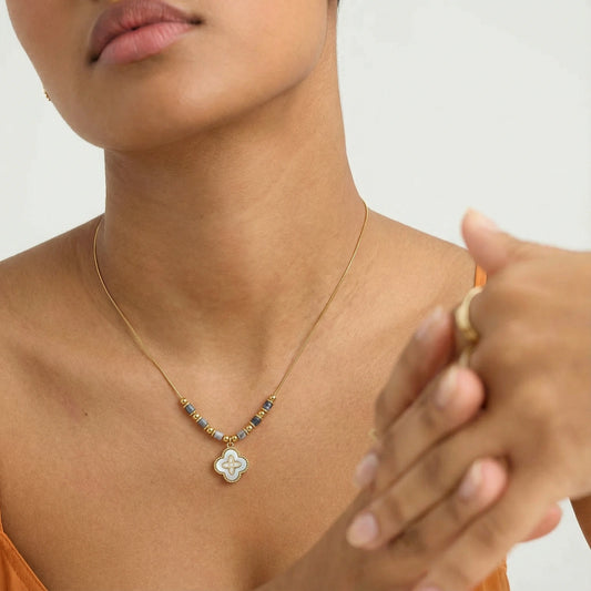 18K gold-plated cloverleaf necklace with abalone pendant by flyliving, featuring grey and gold beads, worn by a person.