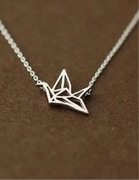 Die silberne flyliving Halskette „Wilhelm“ mit einem filigranen Kranich-Anhänger aus 925 Sterling Silber präsentiert sich elegant auf braunem Hintergrund.