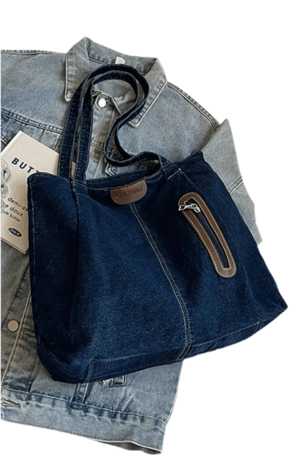 Die flyliving Handtasche „Blue Jeans“, medium, für Frauen, ist eine dunkelblaue Denim-Tote mit braunen Akzenten, Frontreißverschlussfach, zwei Henkeln und dezentem Logo – platziert auf einer hellblauen Jeansjacke.