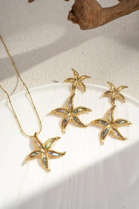 Cosmos Seestern-Halskette - Edelstahl & irisierendes Perlmutt, inspiriert vom Seestern-Design, mit schillernden Farben. Präsentiert auf weißem Teller im weichen Sonnenlicht für einen eleganten Look.