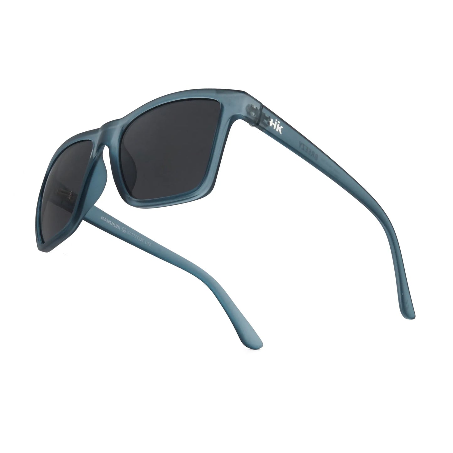 Ein Paar INDICOM BRANDS SL Sonnenbrille Breezy Blue Hanukeii mit mattblauem Rahmen, schwarzen UV400-Gläsern aus Polycarbonat und einem gebogenen Design. Der linke Bügel weist eine kleine weiße Schrift in der Nähe des Scharniers auf. Abgebildet aus einem hinteren Seitenwinkel.