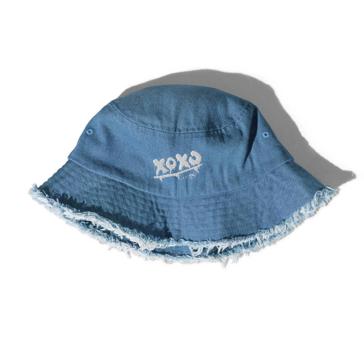 Fischerhut in Light Denim mit gesticktem „XOXO“ und Fransenrand, seitlich liegend fotografiert