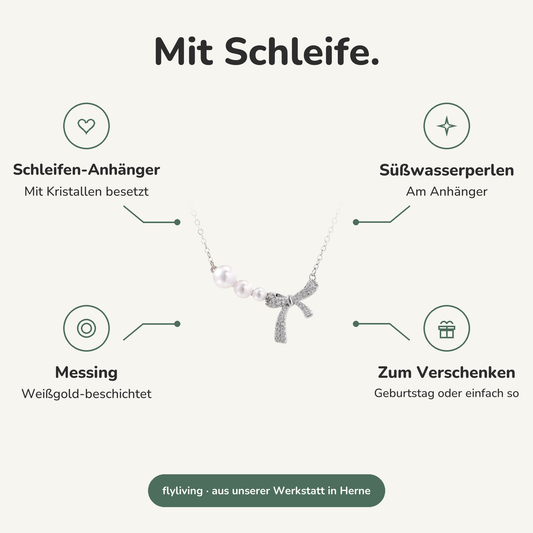 Erklärbild Mit Schleife. Schleifen-Anhänger: Mit Kristallen besetzt, Süßwasserperlen: Am Anhänger, Messing: Weißgold-beschichtet, Zum Verschenken: Geburtstag oder einfach so