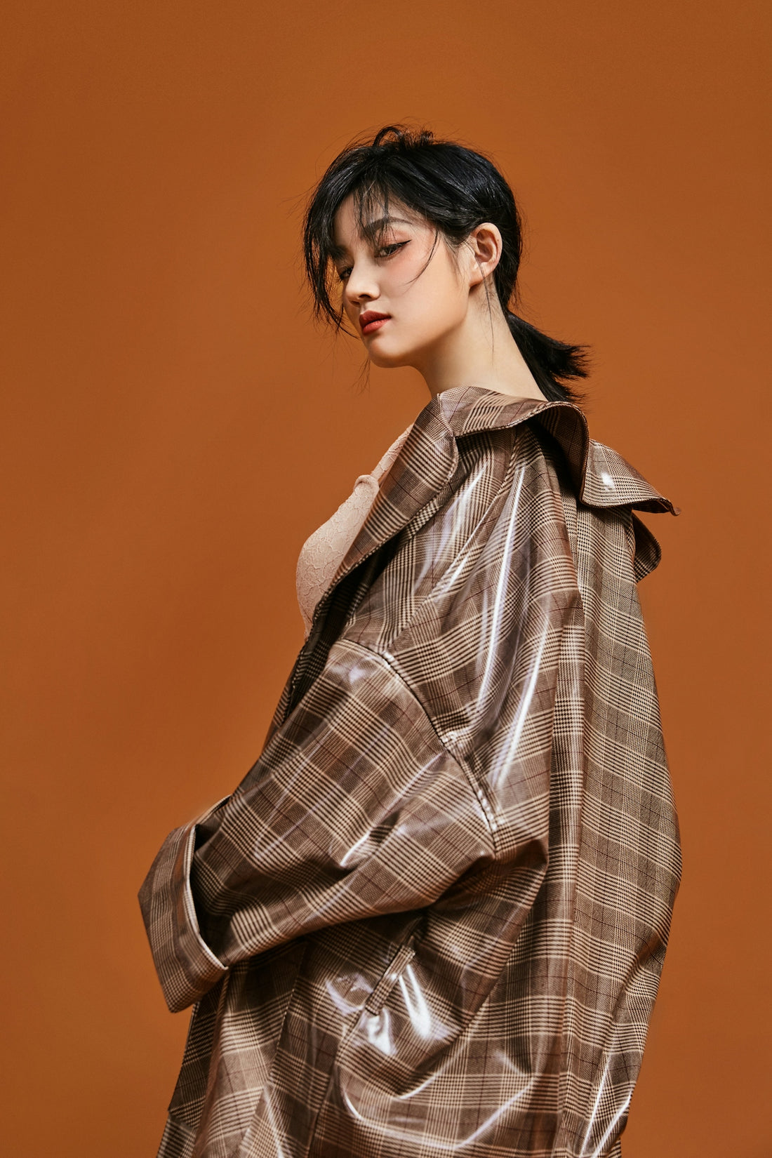 a woman in a brown jacket standing against a brown background