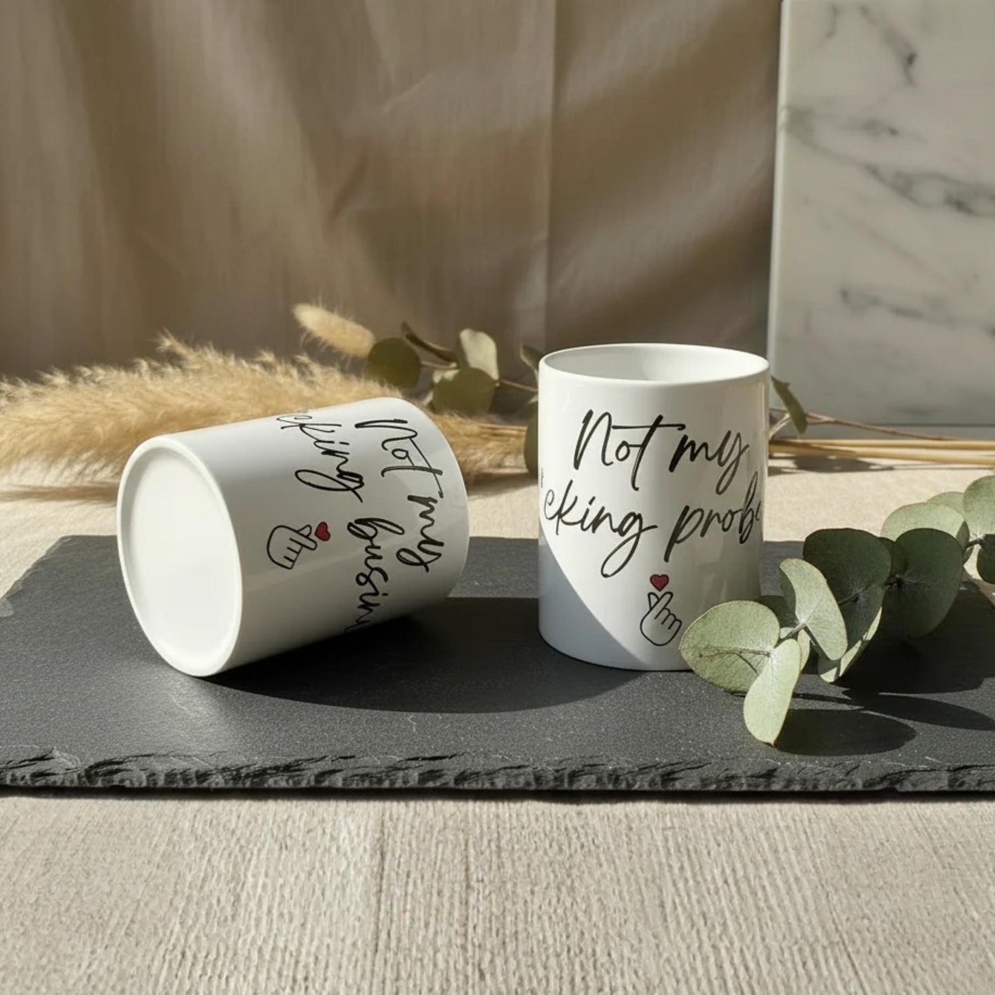 Weiße keramiktasse mit schwarzem kursivtext not my f*cking problem und roten herz-akzenten 325 ml