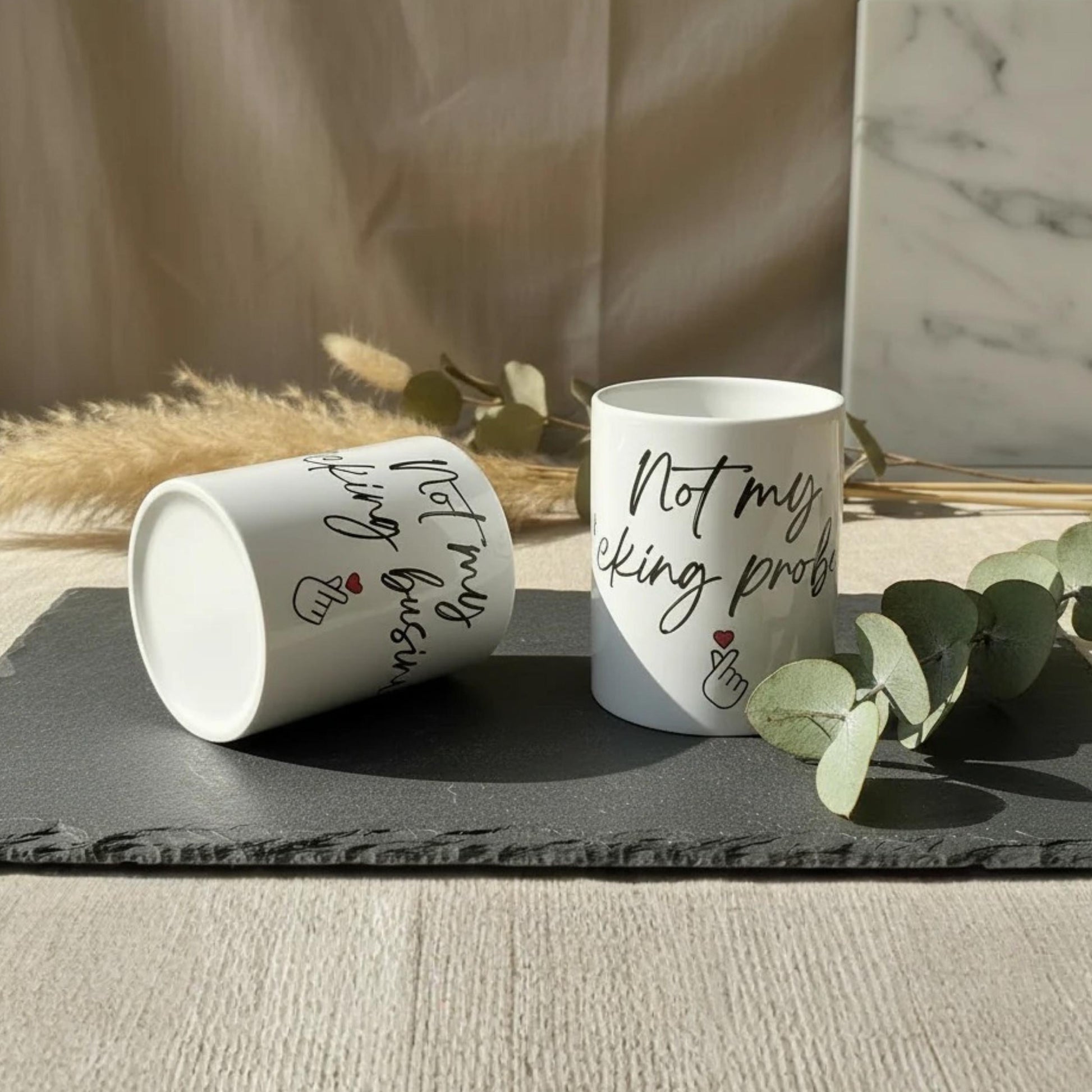 Weiße keramiktasse mit schwarzem kursivtext not my f*cking problem und roten herz-akzenten 325 ml