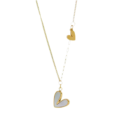 Die goldene Halskette „Uschi“ von flyliving präsentiert zwei Edelstahl-Herzan-Anhänger, ein größeres mit Muscheleinlage und ein kleineres, an einer filigranen Kette – stilvoll inszeniert vor schwarzem Hintergrund.