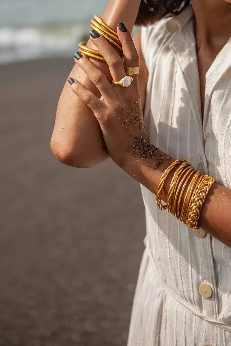 Goldene und silberne Armreifen am Handgelenk einer Person auf hellem Holzfußboden – eleganter Schmuck für Damen, modernes Armband-Design