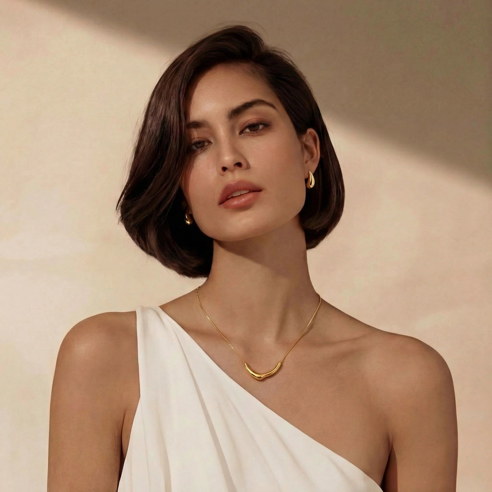 Golden teardrop earrings by flyliving, worn by a model with a matching gold necklace and white top.