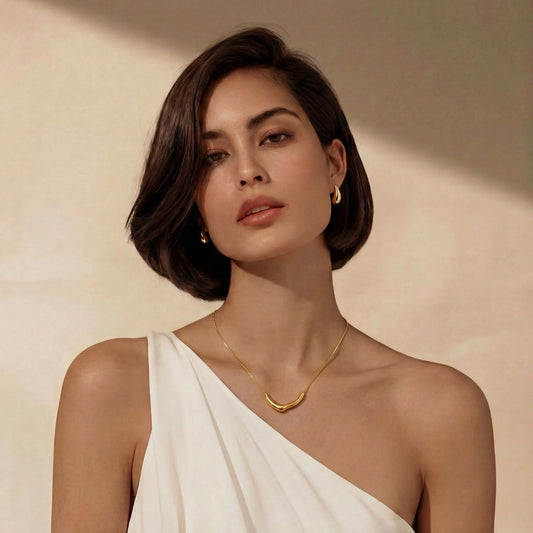 Golden teardrop earrings by flyliving, worn by a model with a matching gold necklace and white top.