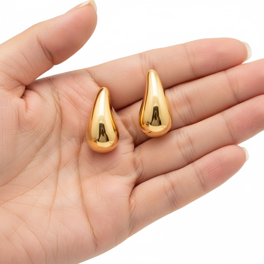 Golden teardrop 18K gold-plated stud earrings by flyliving, smooth and reflective, held in a palm.