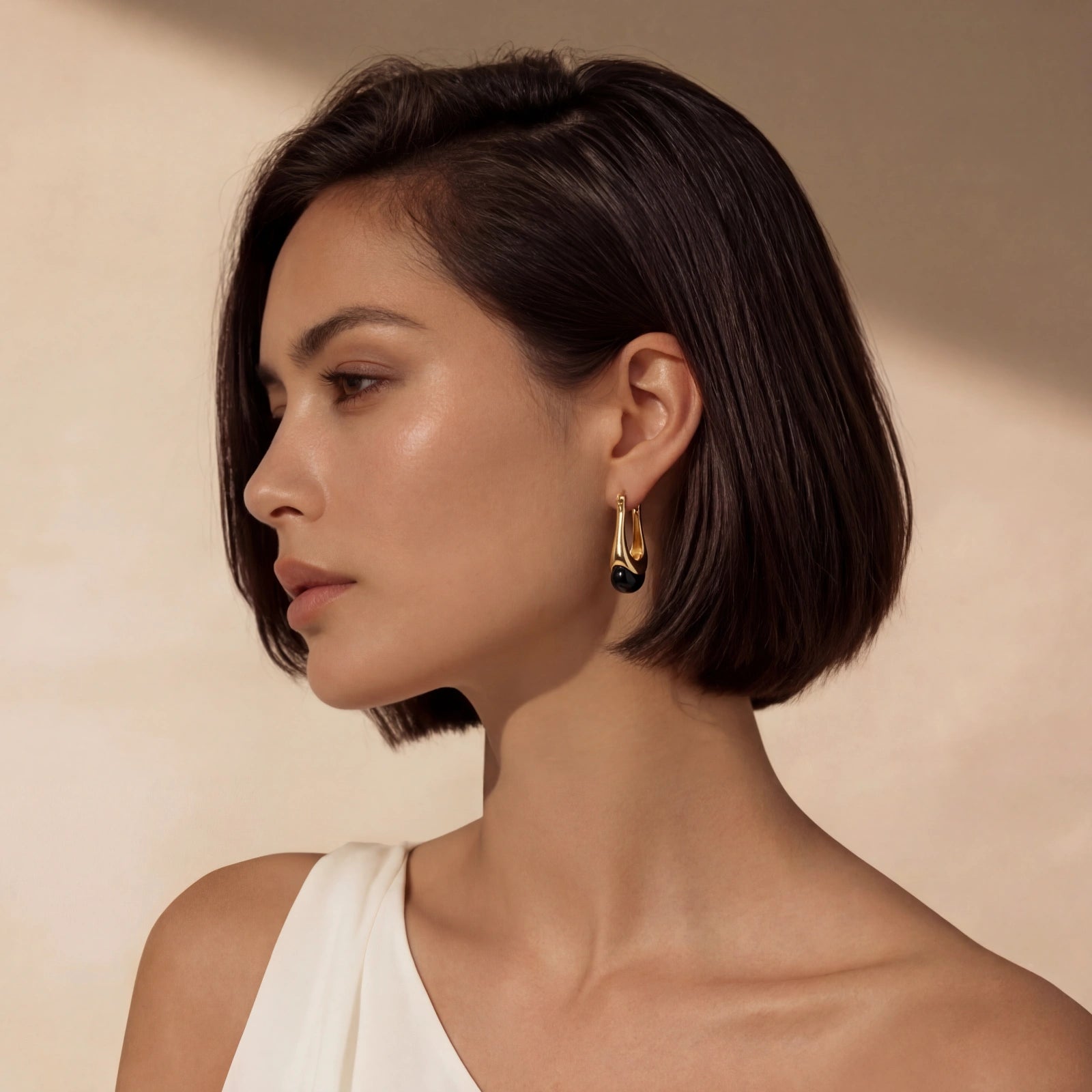 Gold-plated drop earrings with black agate by flyliving, worn by a woman in a side profile.