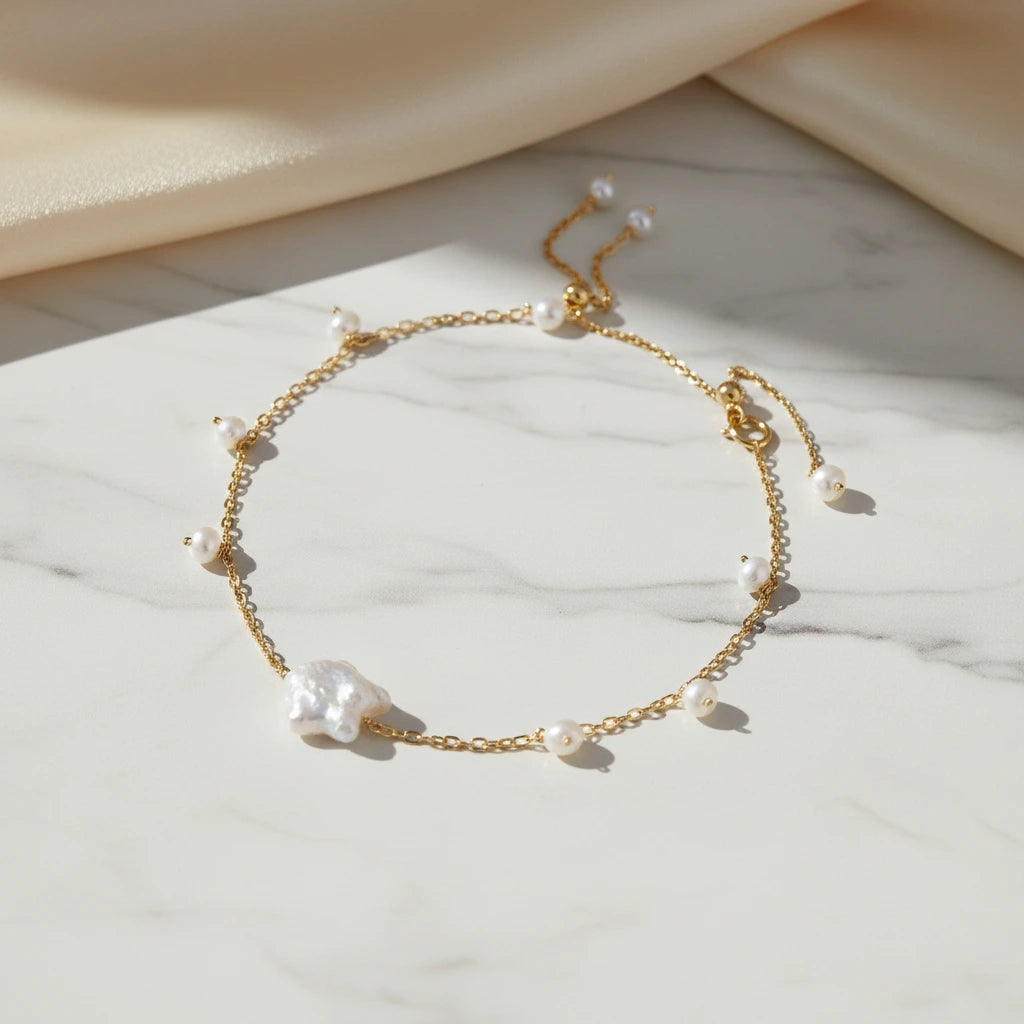 Goldenes Perlen Harmony Armband von flyliving, mit einem großen Barockperlen-Akzent auf einem Marmoruntergrund.
