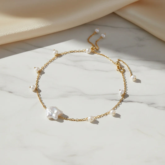 Goldenes Perlen Harmony Armband von flyliving, mit einem großen Barockperlen-Akzent auf einem Marmoruntergrund.
