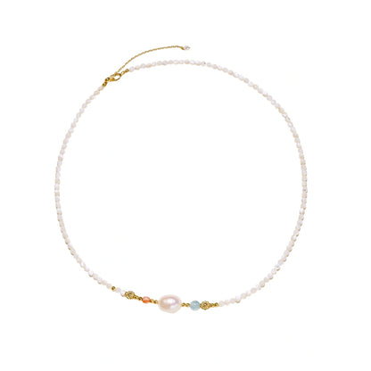Delicate white beaded necklace with baroque pearl center, gold accents, and coral and aqua gemstones on cream background.