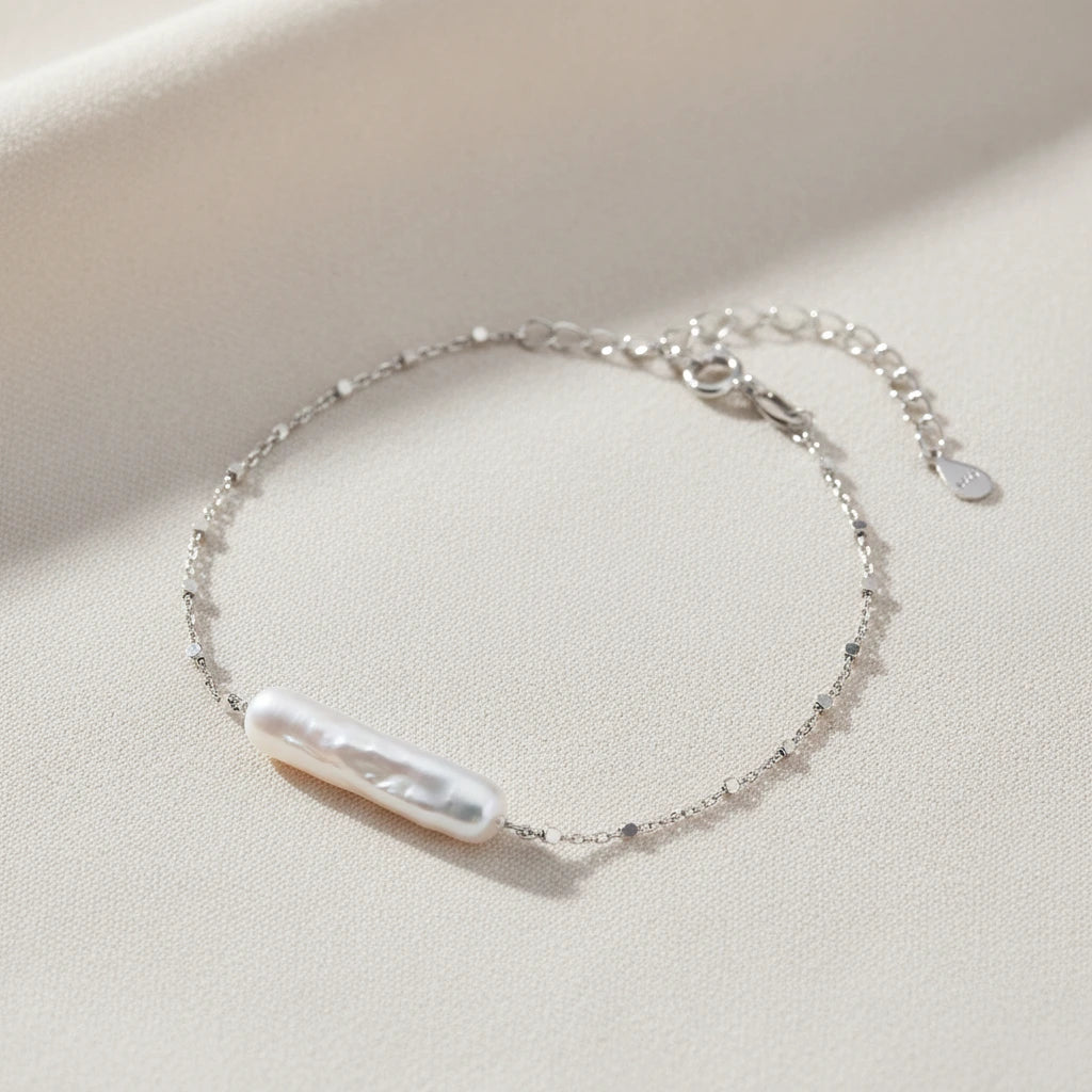 Barock-Perlenarmband von flyliving mit filigraner Silberkette und Knebelverschluss auf beigem Stoff.