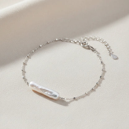 Barock-Perlenarmband von flyliving mit filigraner Silberkette und Knebelverschluss auf beigem Stoff.