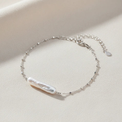 Barock-Perlenarmband von flyliving mit filigraner Silberkette und Knebelverschluss auf beigem Stoff.
