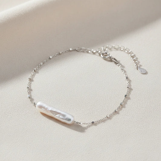 Barock-Perlenarmband von flyliving mit filigraner Silberkette und Knebelverschluss auf beigem Stoff.