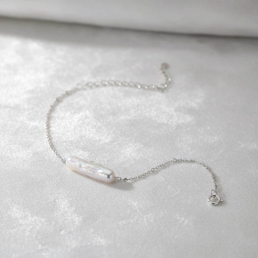 Barockes Perlenarmband von flyliving, mit silberner Kette und Karabinerverschluss auf weißem, samtigem Hintergrund.
