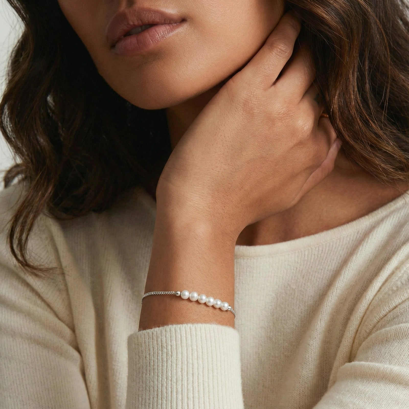 Perlenarmband mit silberner Kette von flyliving, getragen am Handgelenk mit hellem Strickpullover.