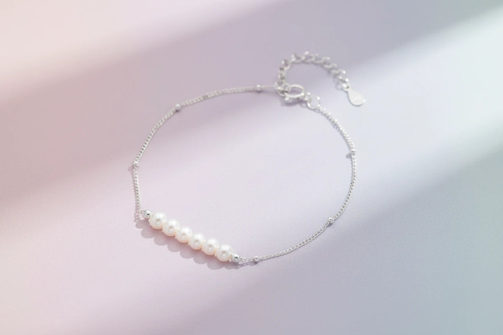 Perlenarmband von flyliving, mit silberner Kette und einem Band aus sechs weißen Perlen.