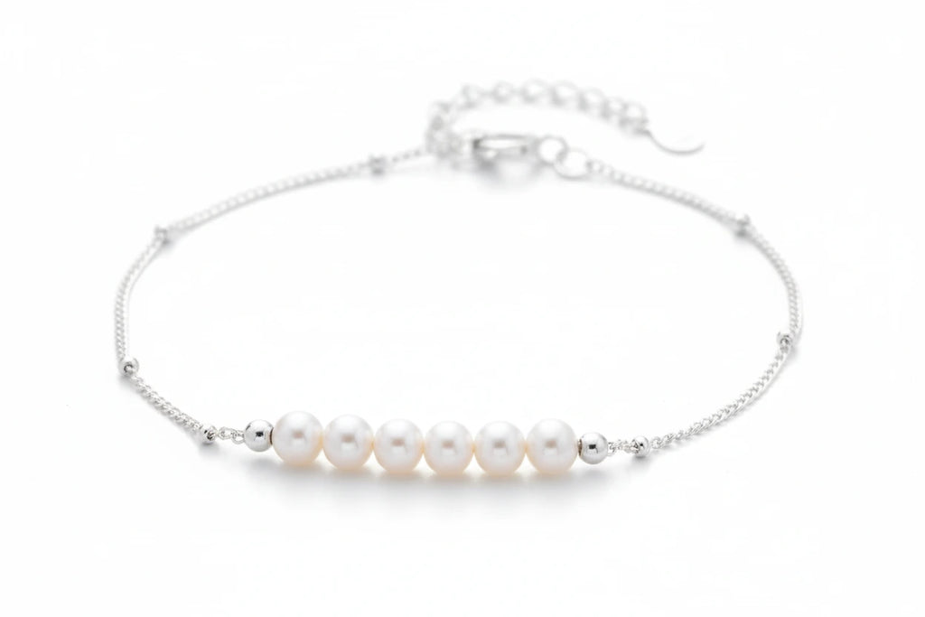 Perlarmband mit silberfarbener Kette von flyliving, verziert mit kleinen Silberkugeln und sechs weißen Perlen.