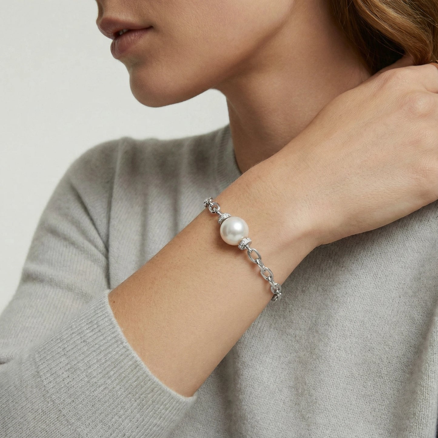 Perlenkettenarmband von flyliving mit silberner Kette und einem glänzenden weißen Perlenakzent, getragen am Handgelenk einer Frau im Profil.
