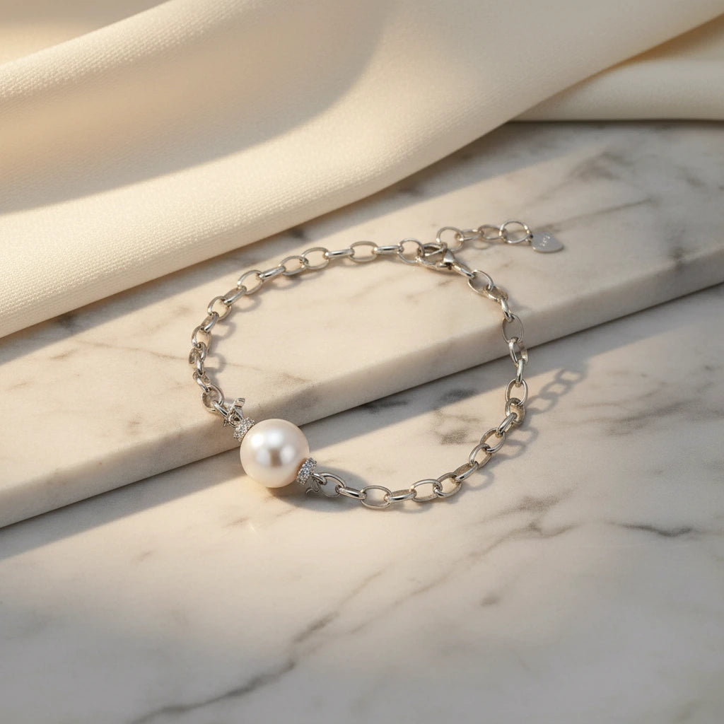 Perlenkettenarmband von flyliving mit silbernen Ketten und Strassverzierungen auf Marmoroberfläche.