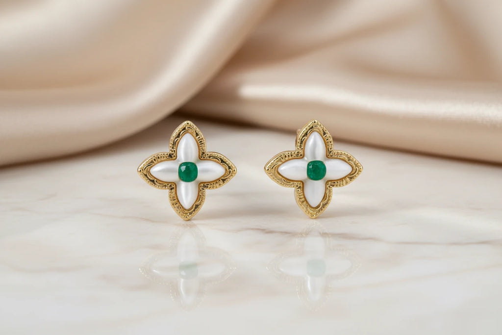 Vergoldete Glücks-Kleeblatt Ohrringe von flyliving mit grünen Akzenten und reflektierender Oberfläche auf Marmor.