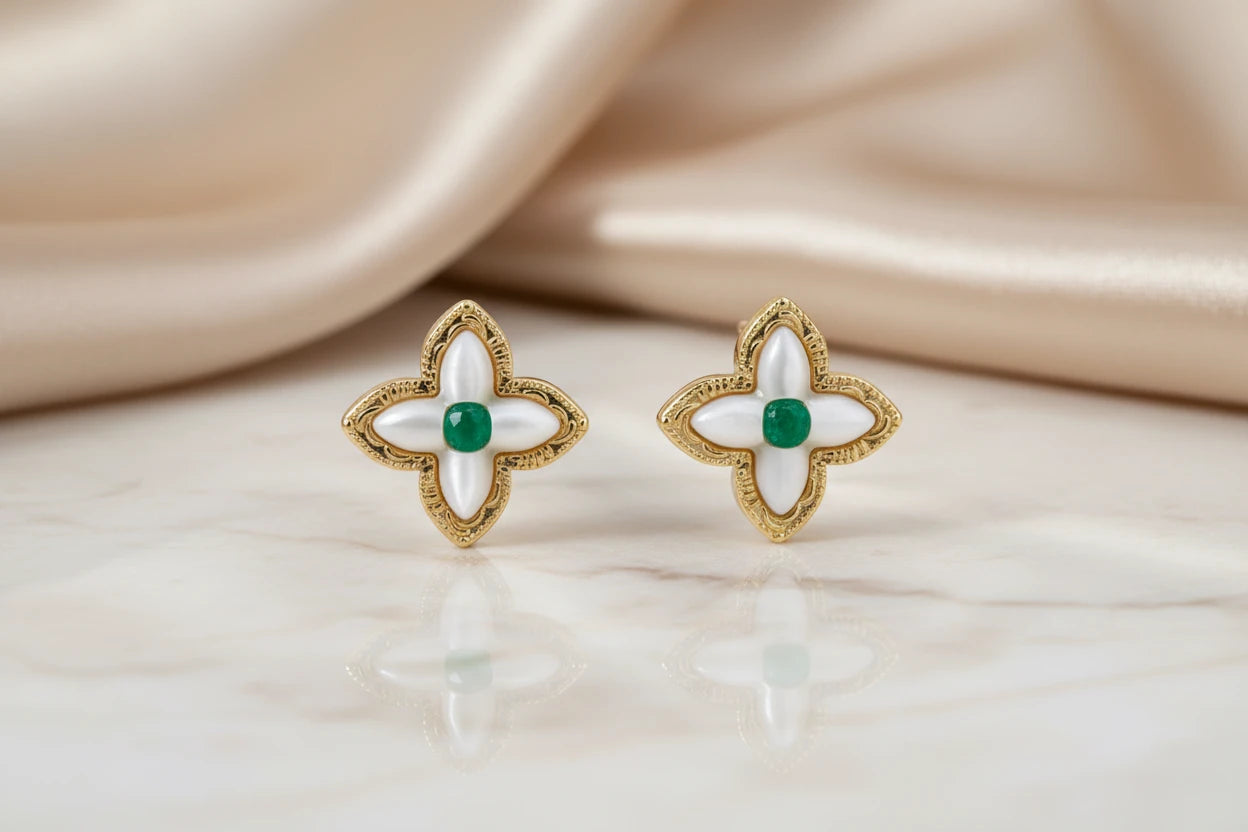 Vergoldete Glücks-Kleeblatt Ohrringe von flyliving mit grünen Akzenten und reflektierender Oberfläche auf Marmor.