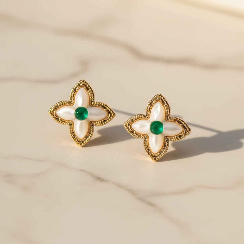 Vergoldete Glücks-Kleeblatt Ohrringe von flyliving mit grünen Akzenten auf marmorähnlichem Untergrund.
