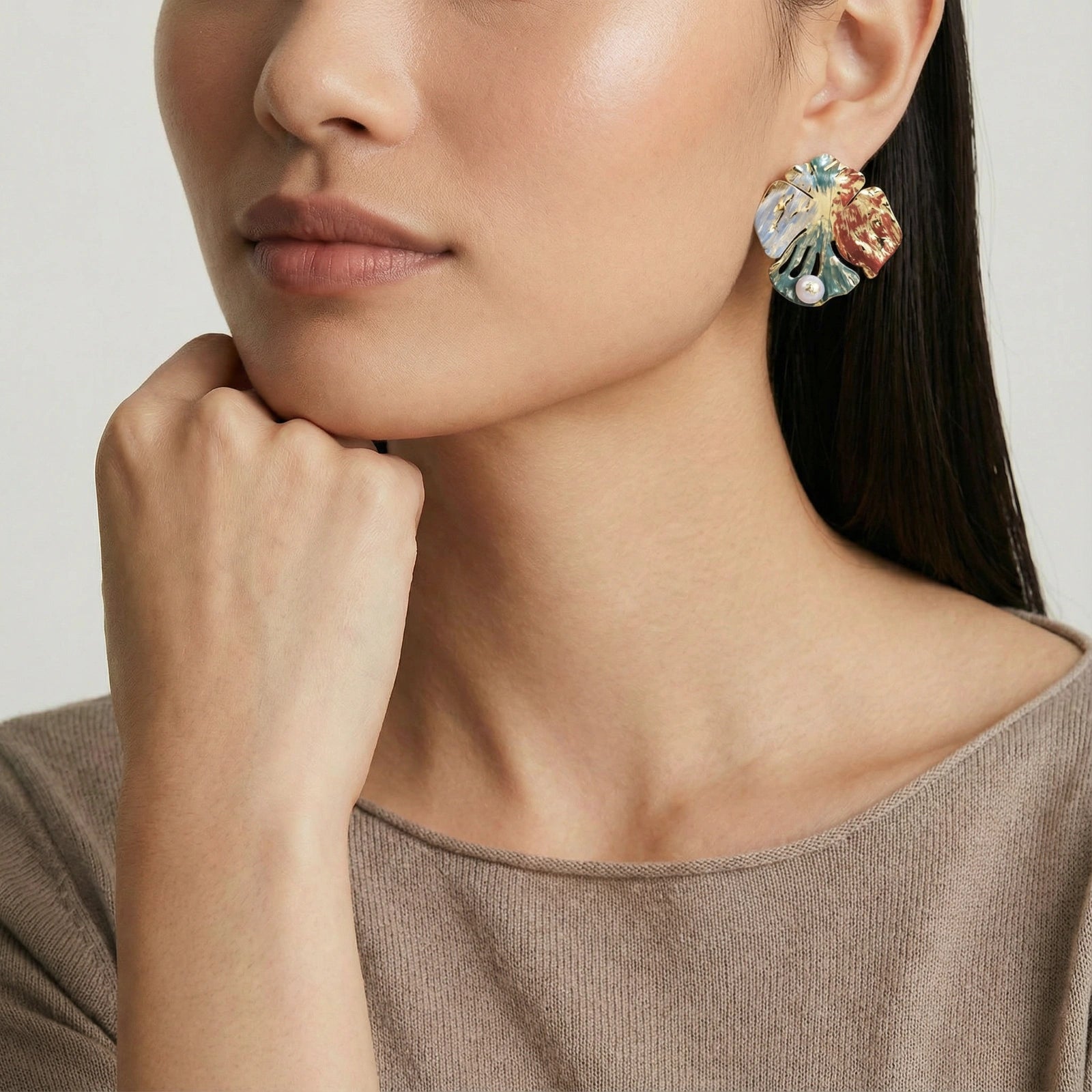 Vergoldete Monstera Muse Ohrringe von flyliving, mit tropischem Blattdesign und zierlicher Perle, getragen von einem Model.
