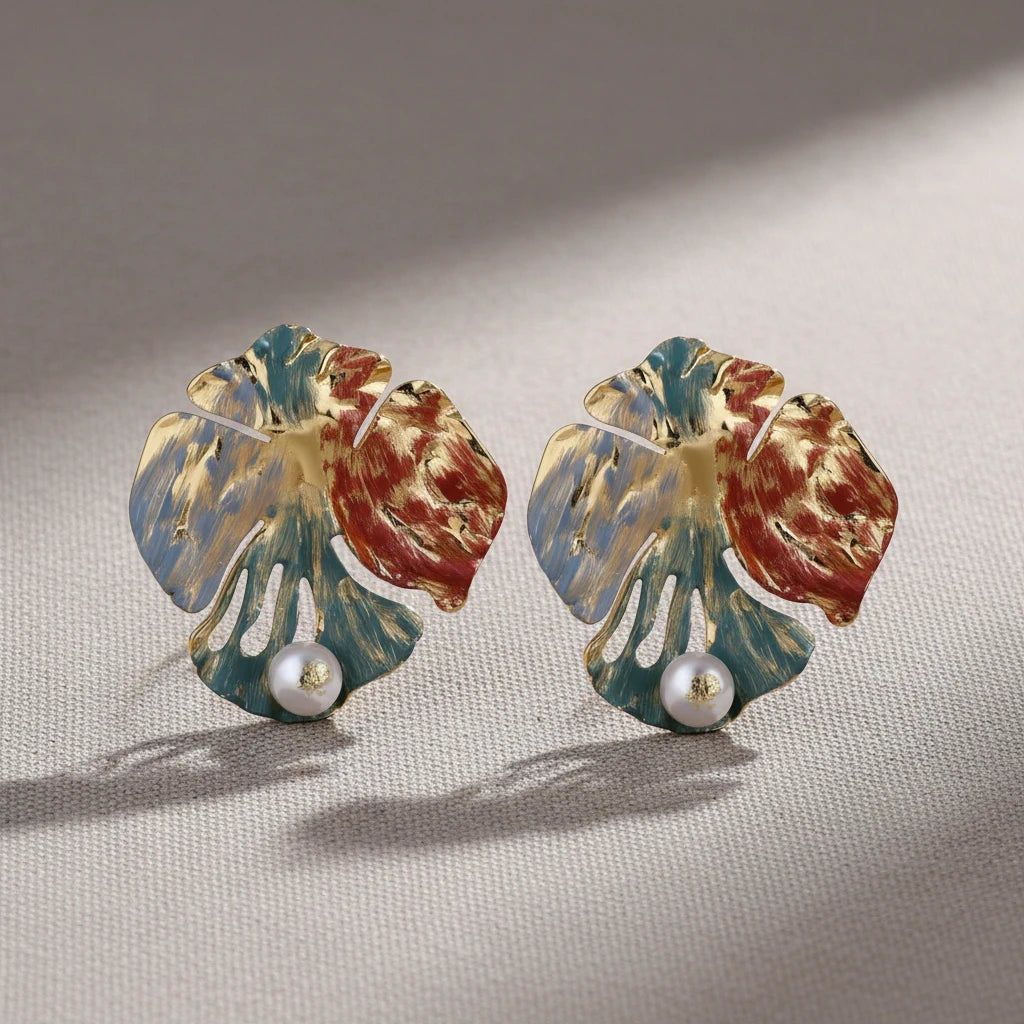 Vergoldete Monstera Muse Ohrringe von flyliving mit blauen, roten und goldenen Akzenten und weißen Perlen.