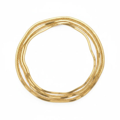 Goldene Halskette von flyliving, mehrreihig und gewunden auf einem weißen Hintergrund.
