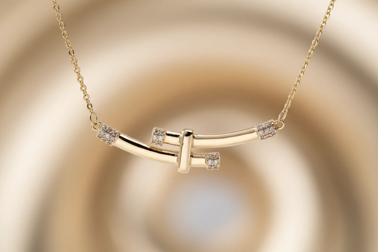 Goldfarbene Bamboo Crystal Arc Halskette von flyliving mit dekorativen Kristallakzenten auf goldenem Hintergrund.