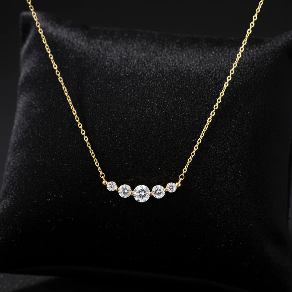 Delicate 14K gold-plated necklace with five graduated zirconia stones arranged in a curved arc on fine chain
