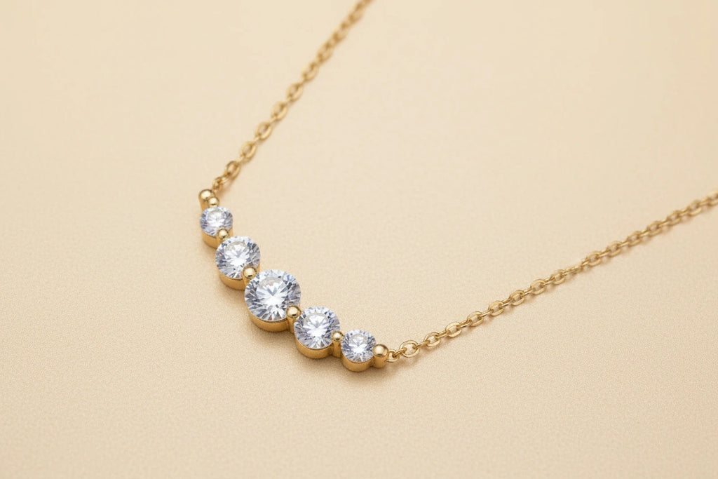 Delicate 14K gold-plated necklace with five graduated zirconia stones arranged in a curved arc on fine chain