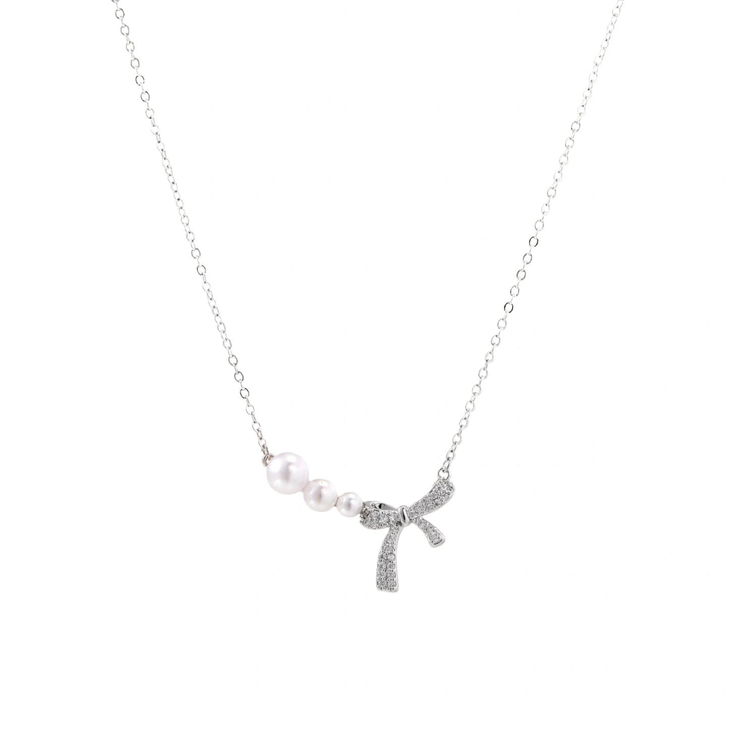 Delicate white gold plated necklace with freshwater pearls and sparkly crystal bow pendant on white background