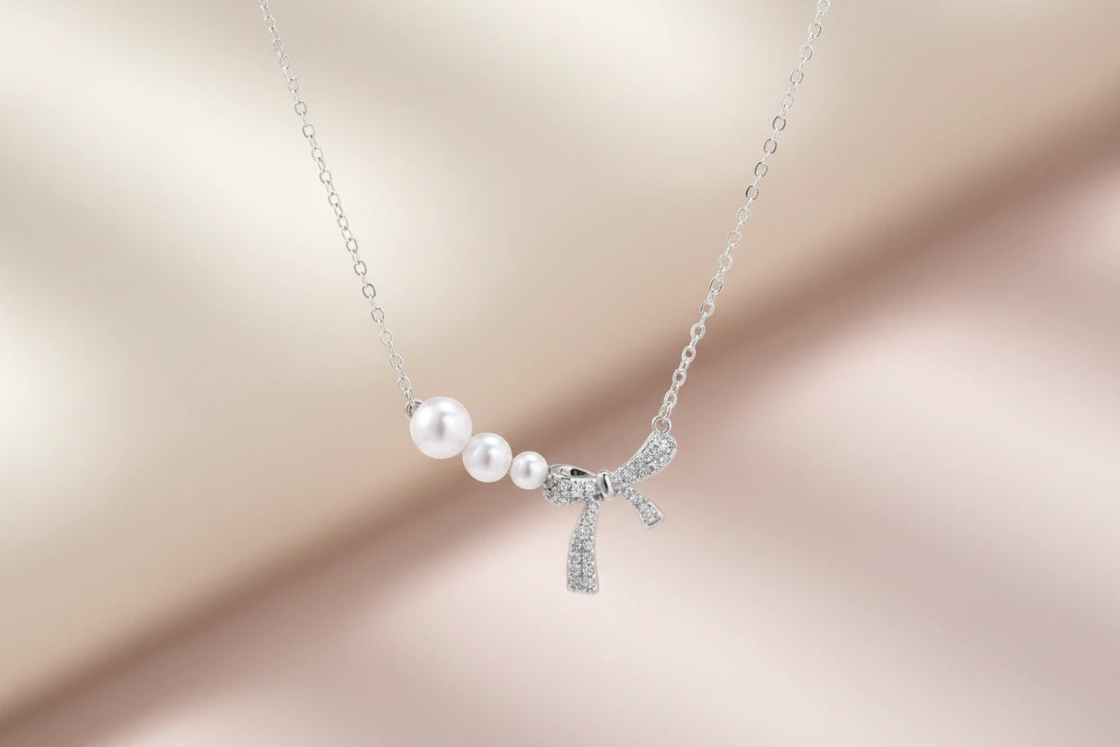 Versilberte Perlen-Schleife Halskette von flyliving, mit drei Perlen und einem Schleifenanhänger.