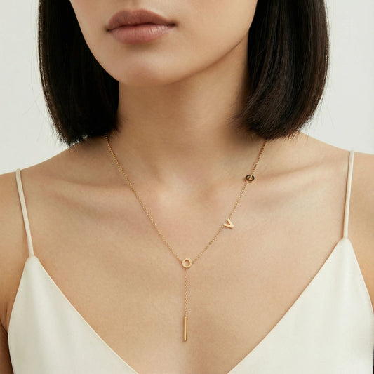 18K gold-plated LOVE Y-chain necklace by flyliving, featuring individual letters and a bar pendant, worn on a woman's neck.