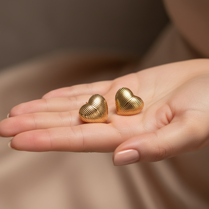 18K gold-plated textured heart earrings by flyliving, featuring a ribbed pattern, held in an open hand with nude polished nails.
