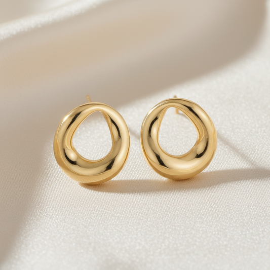 Golden stud earrings by flyliving, featuring an abstract, organic loop design on white fabric.