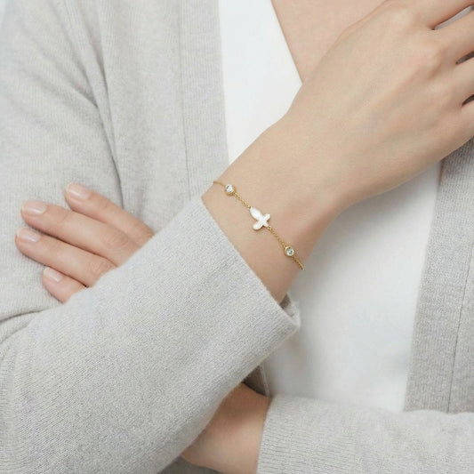 18K gold-plated butterfly bracelet by flyliving, with a mother of pearl charm and two sparkling crystals, on a woman's wrist.