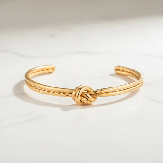 Goldenes Knotenarmband, vergoldet von flyliving, mit gedrehten Details auf einer marmorierten Oberfläche.