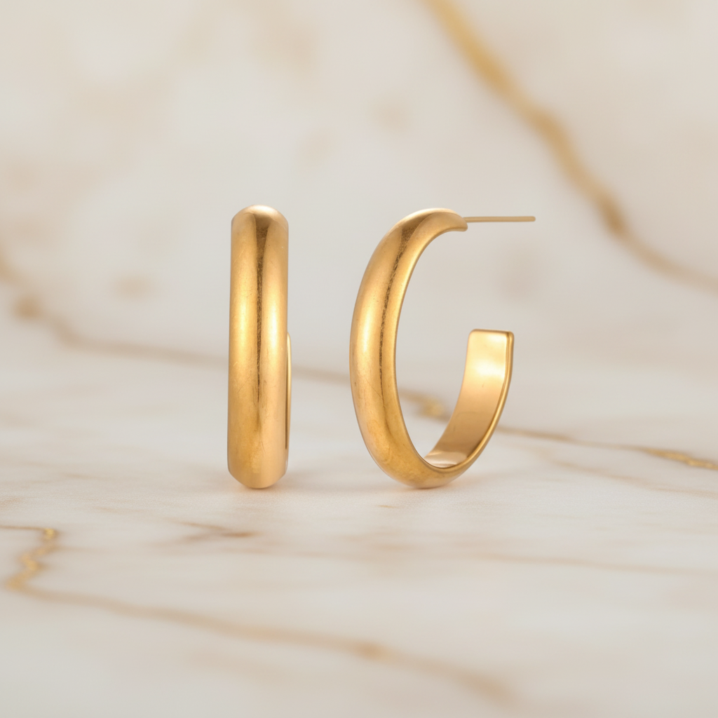 Gold-plated stainless steel hoop earrings by flyliving, displayed as a pair on a marbled surface.