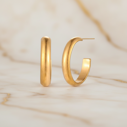 Gold-plated stainless steel hoop earrings by flyliving, displayed as a pair on a marbled surface.