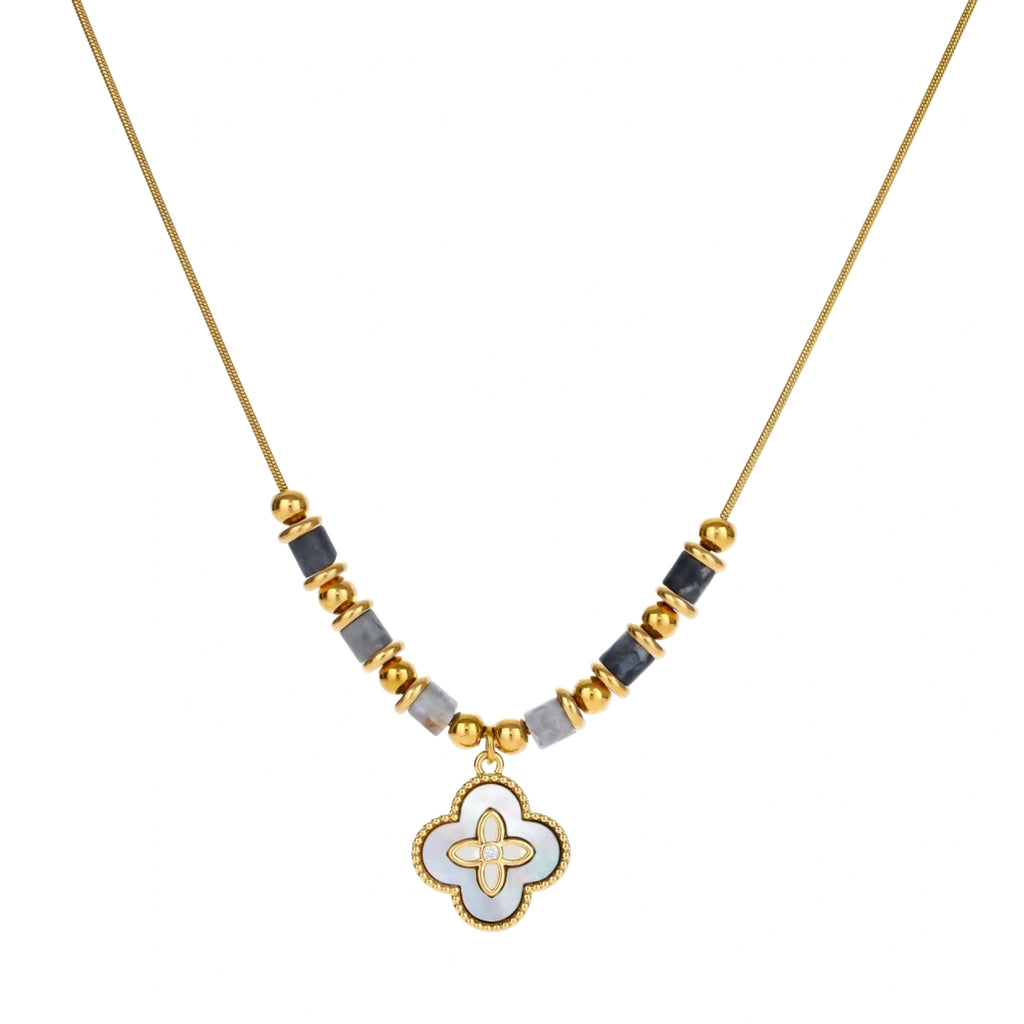 Gold-toned beaded necklace with grey stones and quatrefoil abalone shell pendant on cream background.