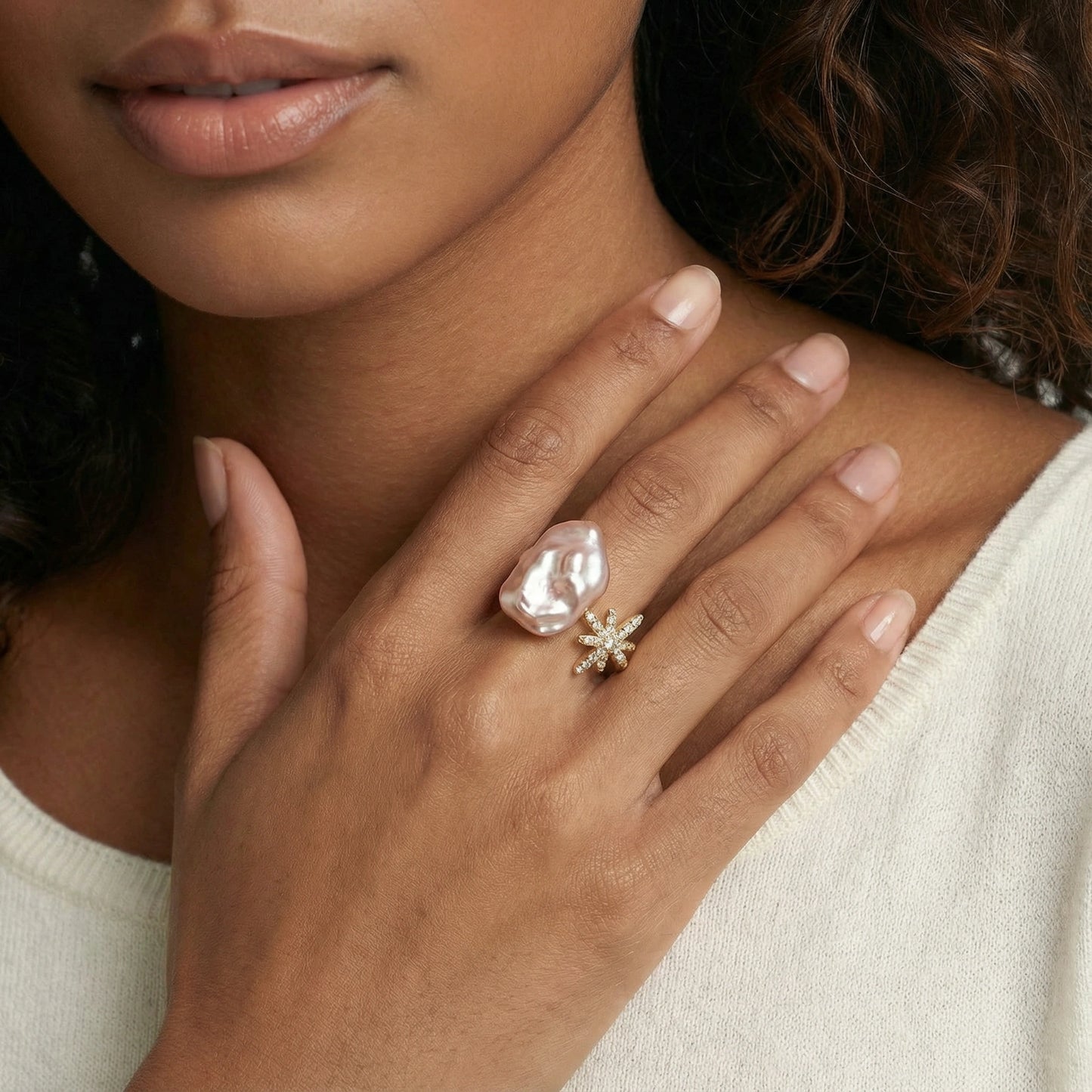 Eine goldfarbene ring mit einer großen unregelmäßigen barockperle und einem funkelnden sternenburst-design